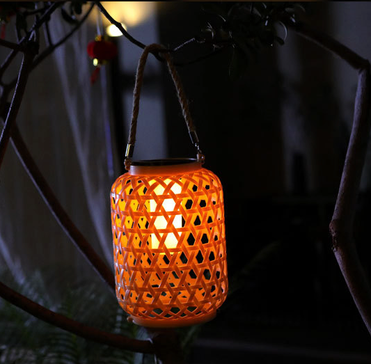 lampe exterieure tiki effet bambou suspensue à une corde la nuit allumée