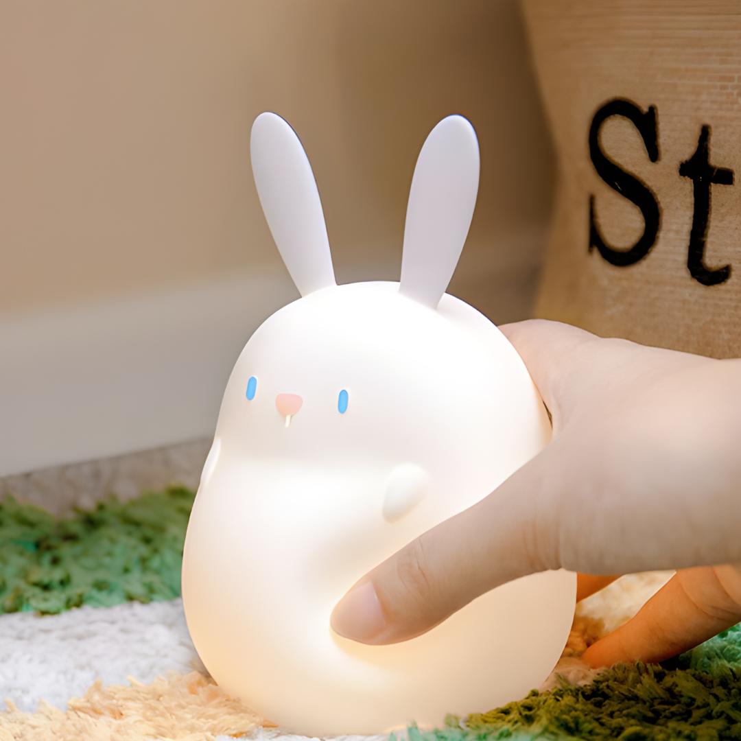 veilleuse lapin blanc dans une main qui appuies dessus pour montrer que le silicone est souple