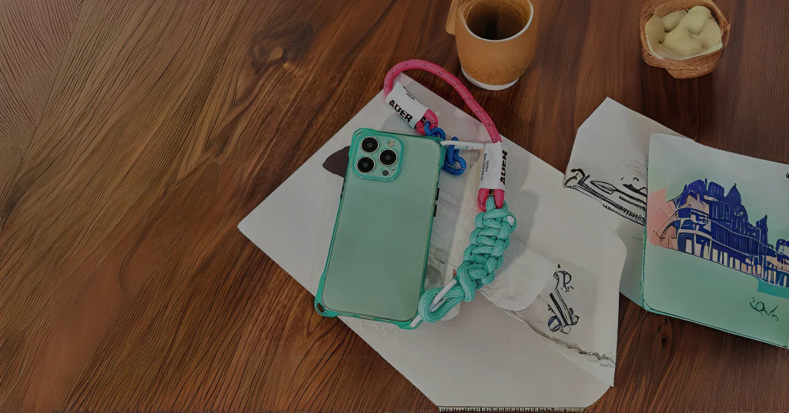 Coque iPhone fluo verte avec cordon rose et turquoise – vue lifestyle sur table en bois