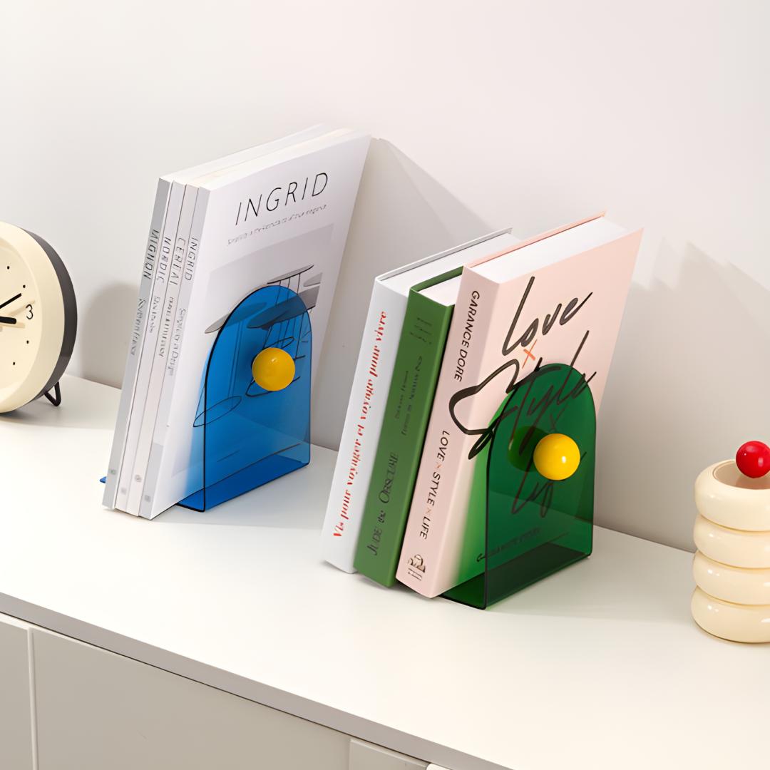 Paire de blocs livres colorés bleu et vert en acrylique avec boules jaunes, utilisés sur une commode blanche.