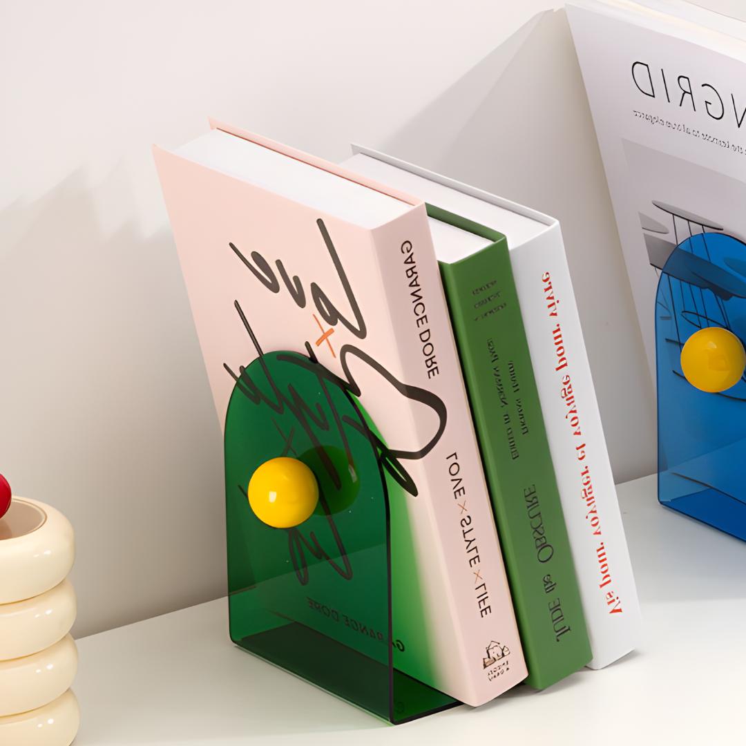 Bloc livres vert avec boule jaune maintenant plusieurs ouvrages sur étagère blanche, modèle bleu en arrière-plan.