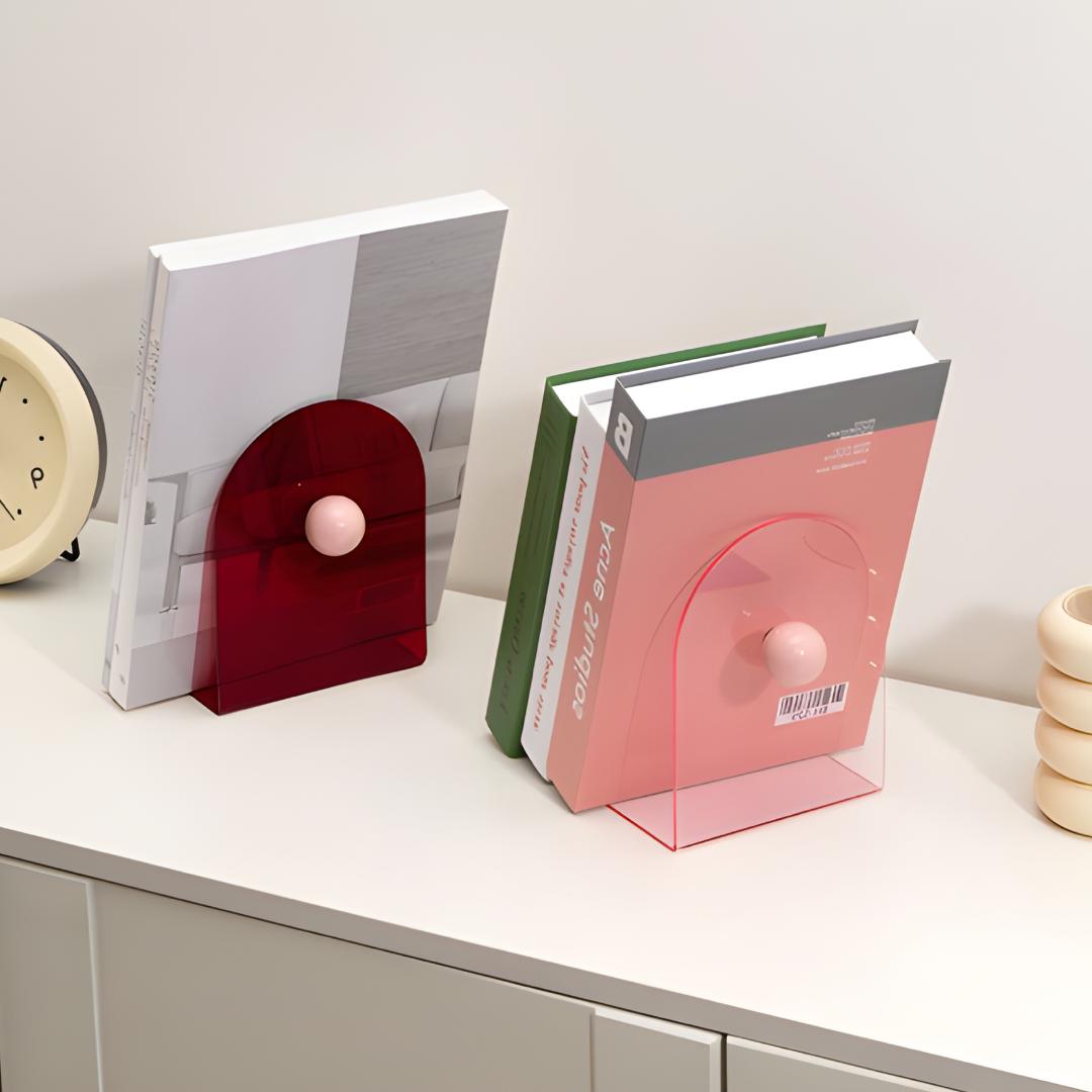 Blocs livres rouge foncé et rose clair avec boules assorties, utilisés en duo sur meuble blanc.