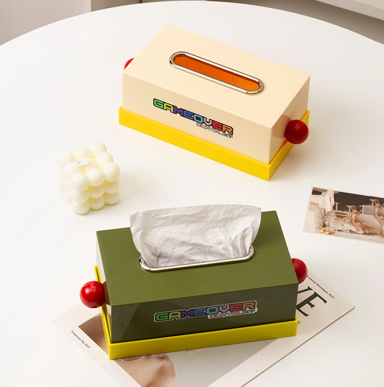 boite à mouchoir style memphis une blanc cassé l'autre verte sur une table blanche avec une bougie blanche sur le coté