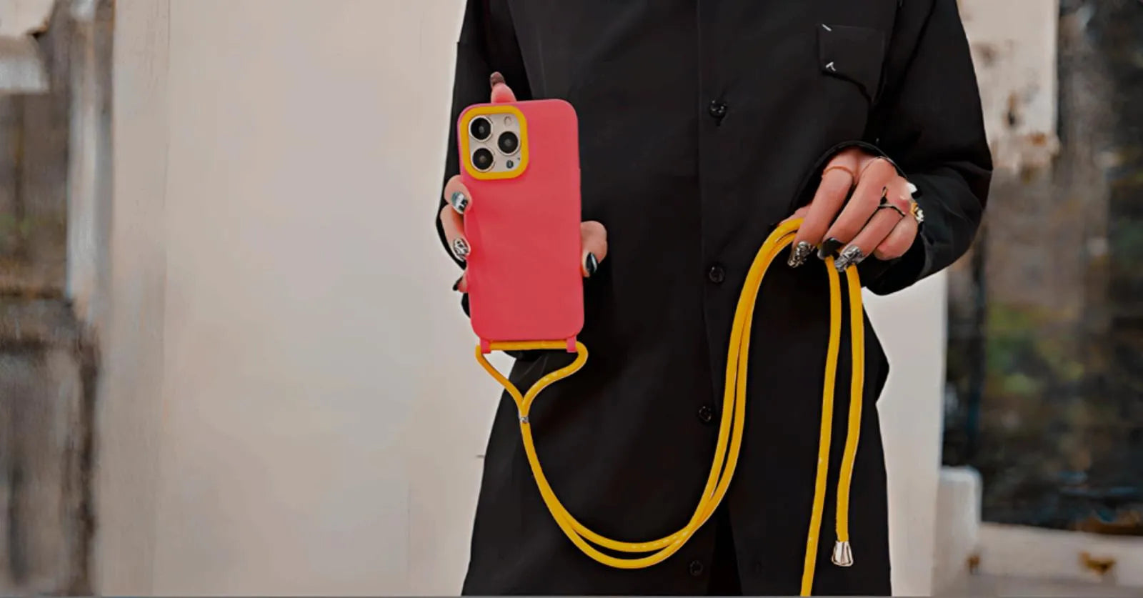 Détail du cordon jaune et de l’attache sur la coque rose, main féminine