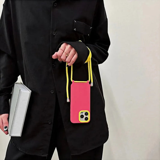Coque iPhone rose et jaune portée à la main, tenue par la bandoulière