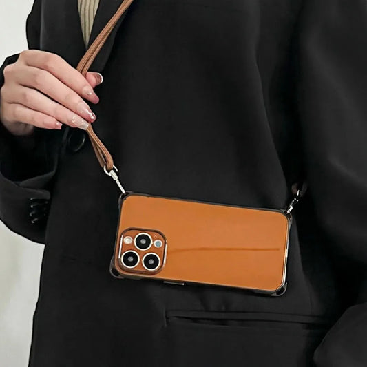 Coque iPhone marron portée à l'épaule avec cordon fin, tenue sur une veste noire