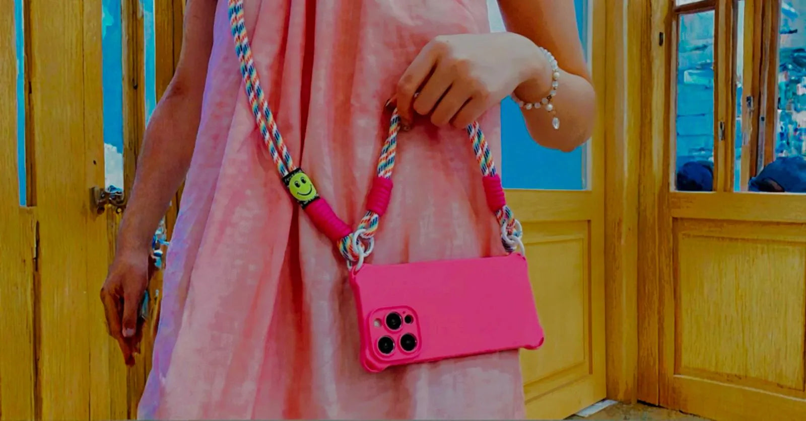 Coque rose fluo portée devant une vitrine boisée, robe rose assortie
