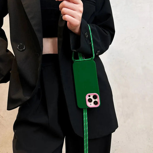 Coque verte avec encadrement rose tenue à la main, cordon bien visible – look full black