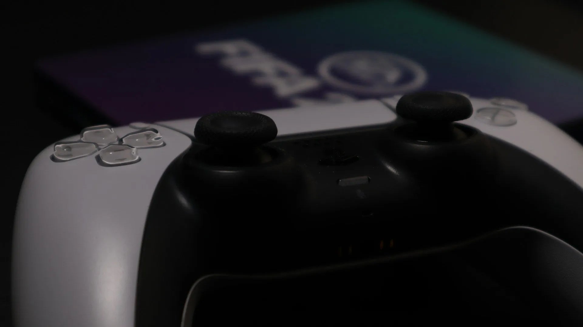 Manette de jeu PS5 en gros plan avec éclairage tamisé sur fond de boîte rétro gaming, ambiance gamer immersive.