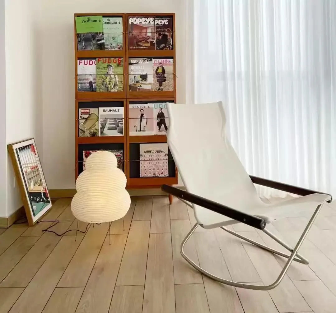 Lampe en papier par terre près d’une bibliothèque, design chaleureux et naturel