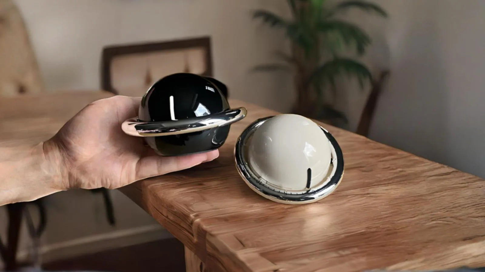 Minuteurs mécaniques design noir et blanc en forme de planète, posés sur une table en bois dans un intérieur chaleureux
