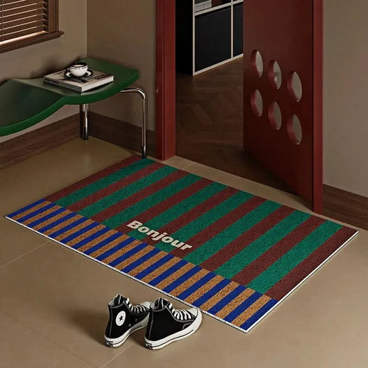Paillasson Bonjour à rayures vertes et rouges dans une entrée au design rétro avec porte rouge ajourée