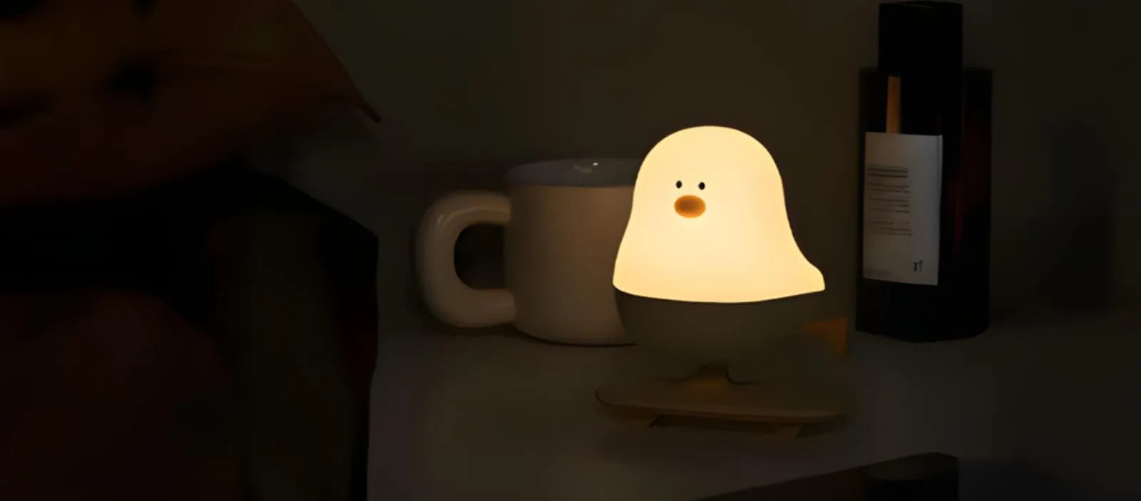 Veilleuse poussin LED sur une table de chevet dans ambiance nocturne minimaliste