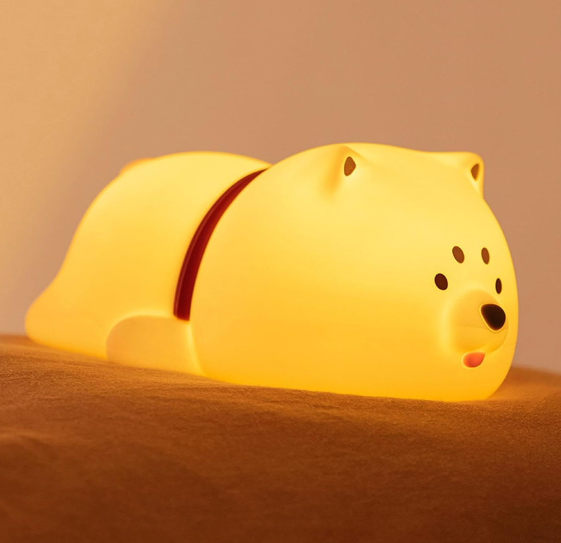 veilleuse chuien posé sur un lit avec des draps couleur orange