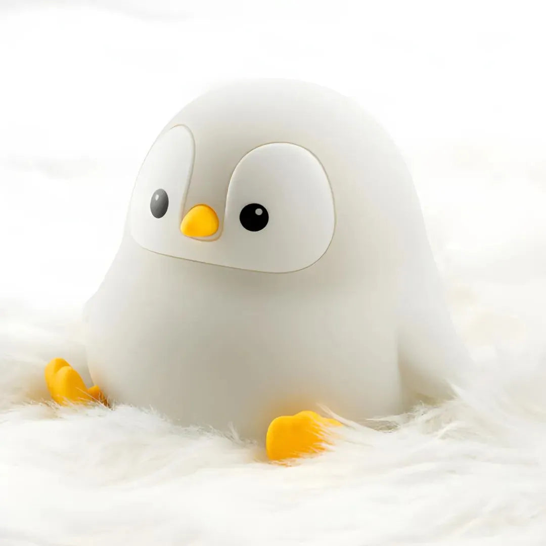 veilleuse originale en forme de pingouin assis éteinte et posée sur un tapis à poils blancs