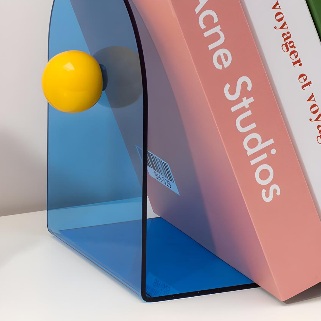 Bloc livres bleu avec boule jaune, utilisé pour maintenir un livre grand format incliné sur étagère.