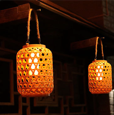 2 lampe exterieure tiki effet bambou suspendues à des clou en exterieur, allumées