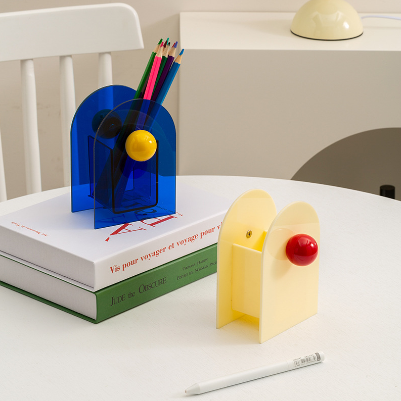 porte stylos style memphis bleu et jaune et un autre blanc et rouge sur table blanche