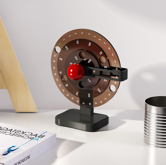 calendrier rotatif couleur foncé 3 cercle version sur bureau avec un livre devant
