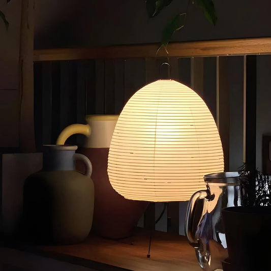 lampe à poser en papier akari noguchi sur comptoir avec pots et plantes en décoration