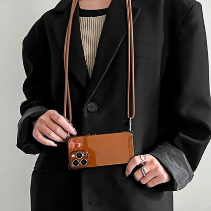 Coque iPhone marron portée à la main, cordon croisé en avant de la veste