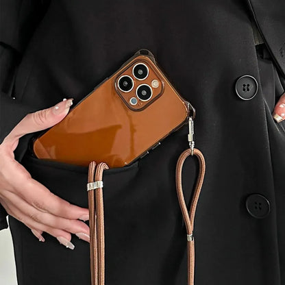 Coque iPhone marron glissée dans une poche de manteau noir, cordon visible