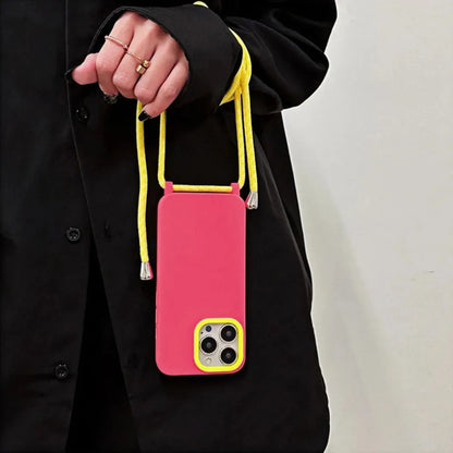 Coque rose fluo avec cordon jaune portée à la main – vue sur tenue oversize