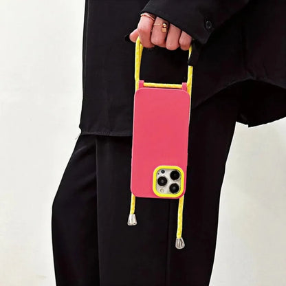 Coque iPhone rose fluo et jaune tenue à la main par le cordon – look mode noir