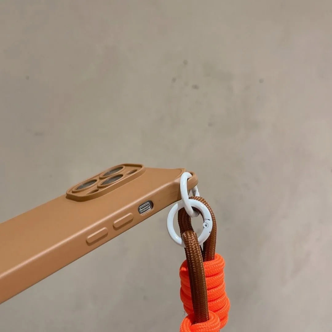 Zoom latéral sur la coque marron, boutons de volume visibles, cordon orange et anneau blanc