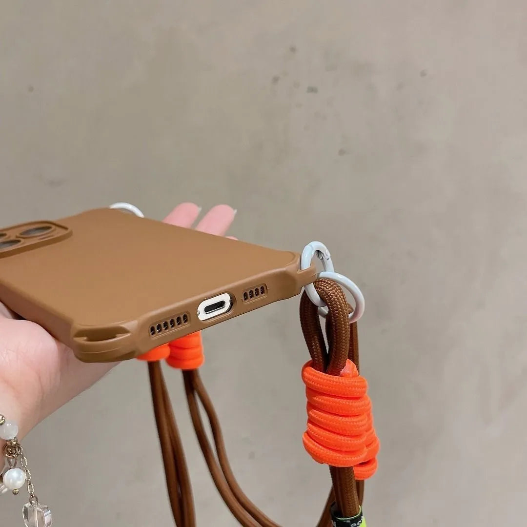 Coque marron en main, vue sur le port de charge et anneaux blancs, cordon orange