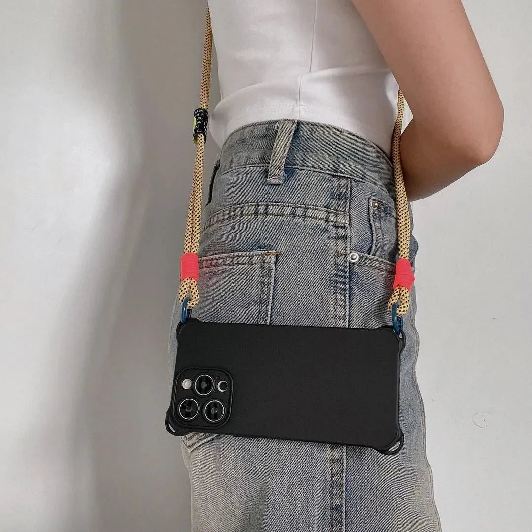 Coque noire portée en bandoulière à l’arrière, cordon jaune fluo avec attaches roses et anneaux bleus