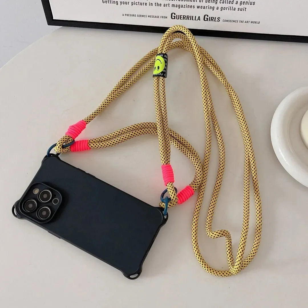 Coque noire posée à plat avec cordon jaune fluo motif quadrillé et badge smiley