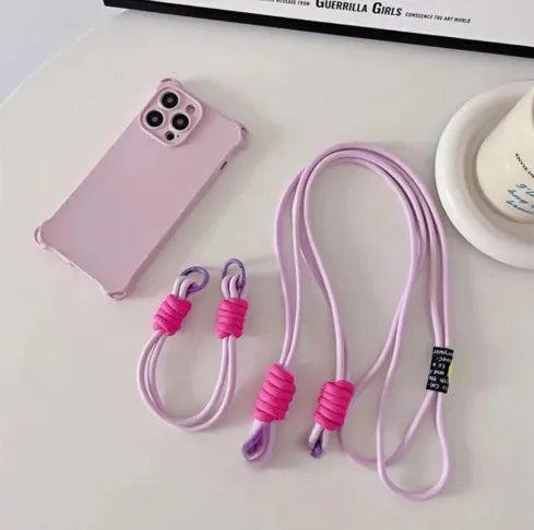 Coque rose pastel avec cordon bandoulière violet et rose fluo en nylon tressé posé sur table blanche
