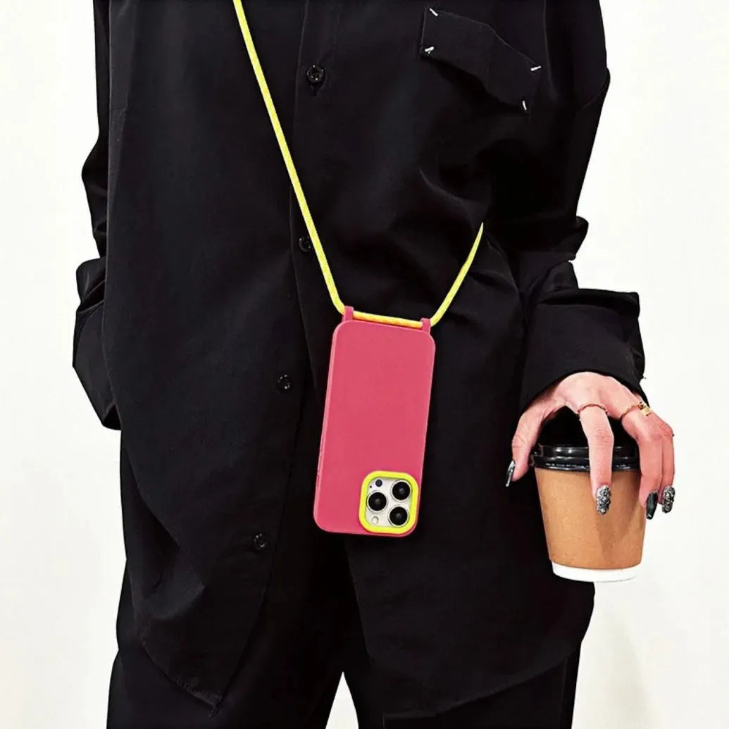 Coque rose fluo avec cordon jaune portée en bandoulière avec tenue noire stylée