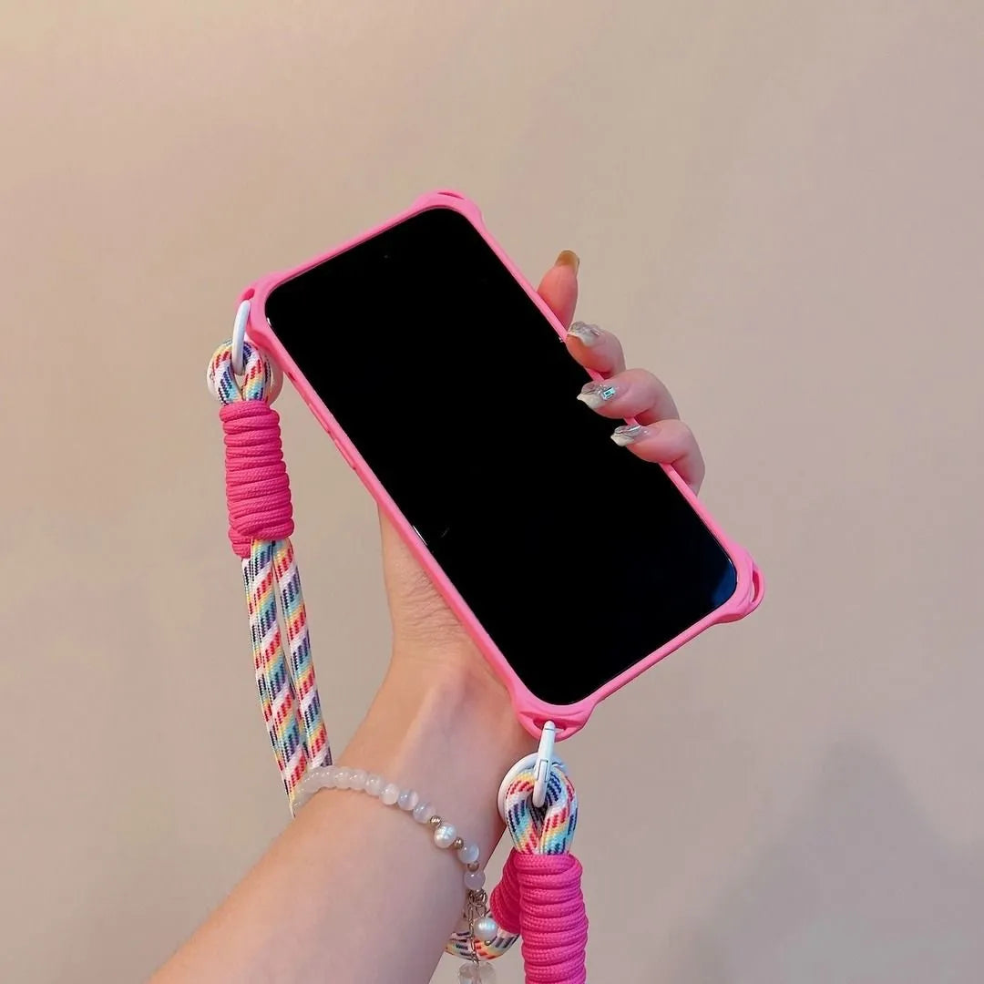 Coque rose fluo tenue en main, écran noir visible, cordon arc-en-ciel enroulé