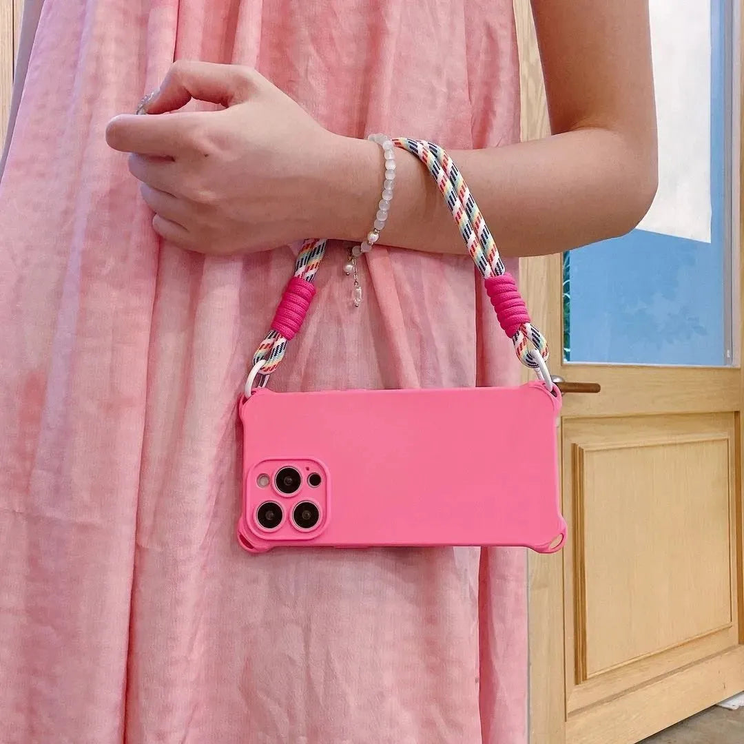 Coque rose fluo tenue à la main, robe rose assortie, cordon arc-en-ciel enroulé