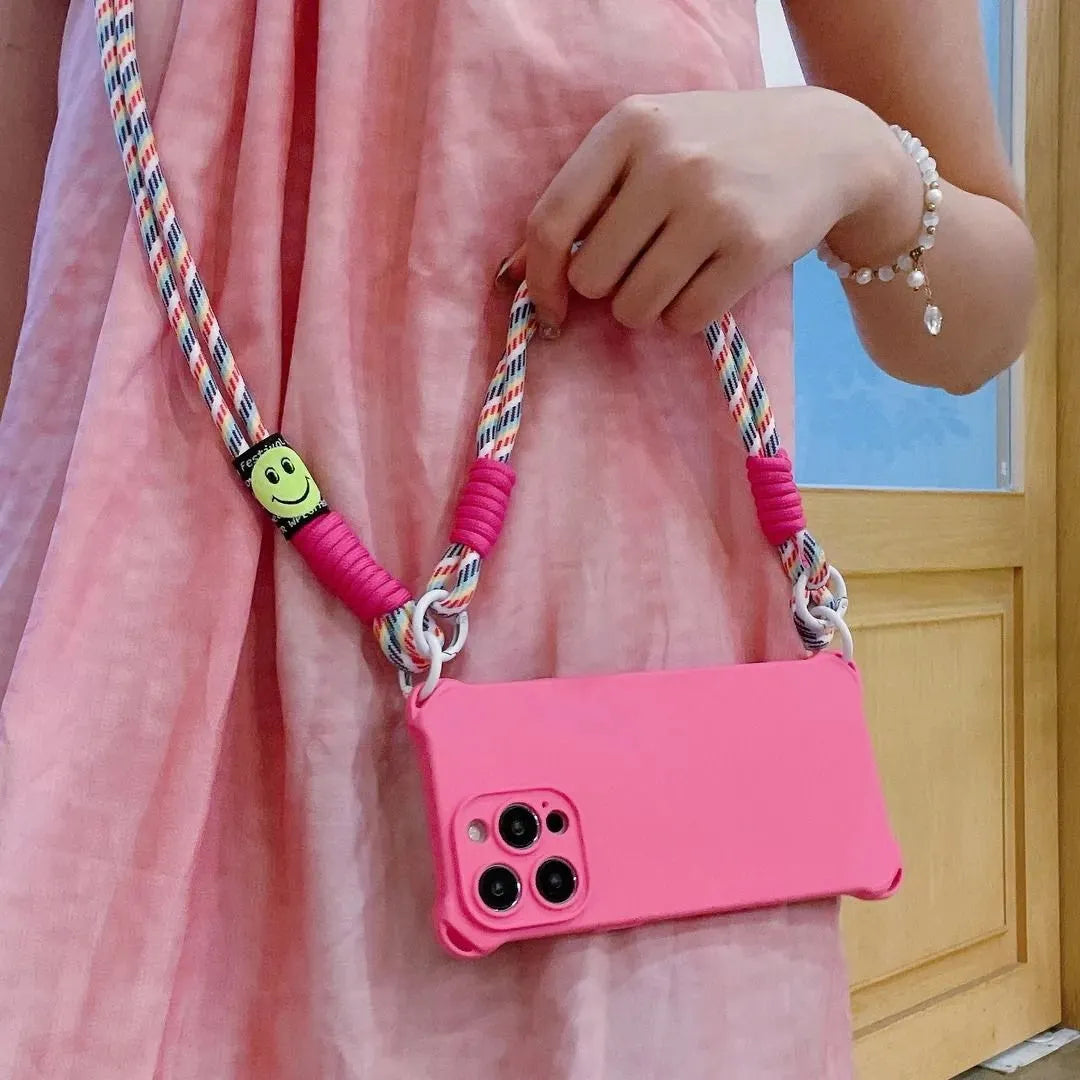 Coque rose fluo portée à la main avec cordon arc-en-ciel, smiley visible