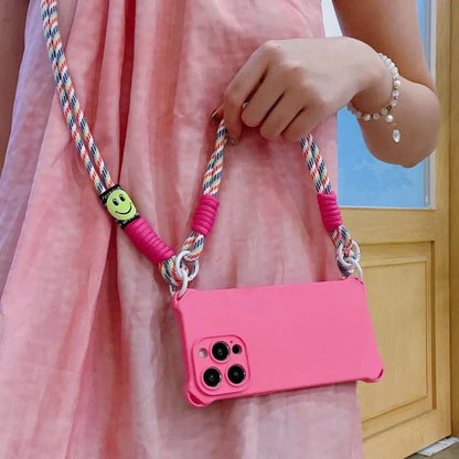 Coque rose fluo portée à la main avec cordon arc-en-ciel, smiley visible