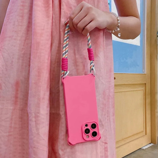 Coque rose fluo tenue par la sangle à la main, robe rose en fond
