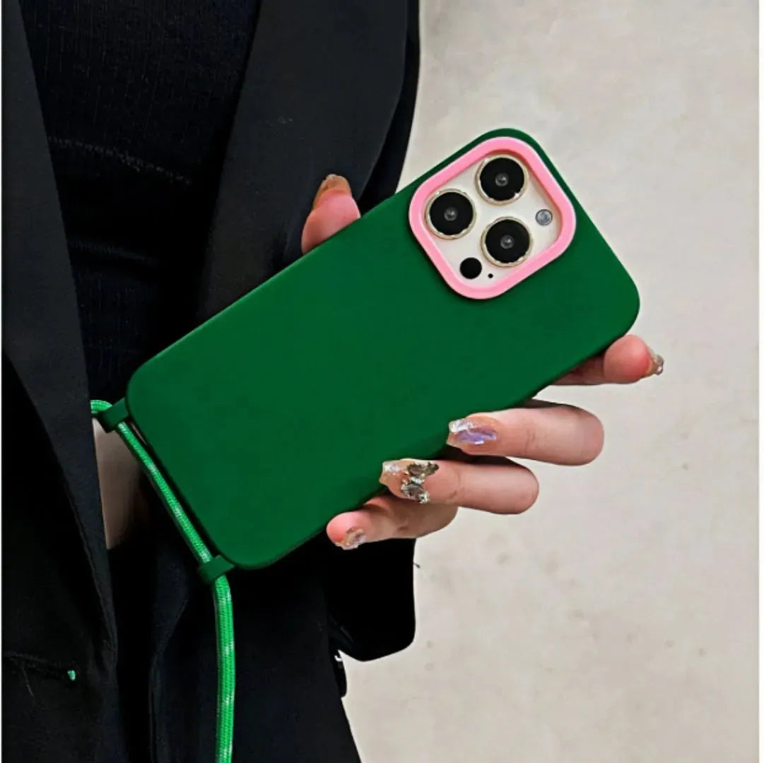 Coque verte avec cordon tenue à la main, encadrement rose visible, look noir en arrière-plan