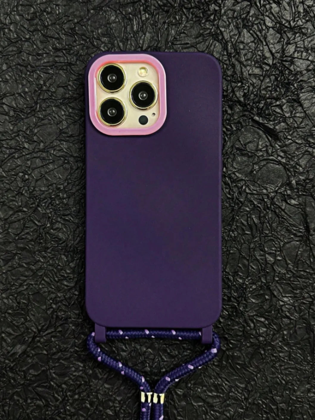 Zoom sur la coque violette et cordon réfléchissant, posée sur fond texturé noir
