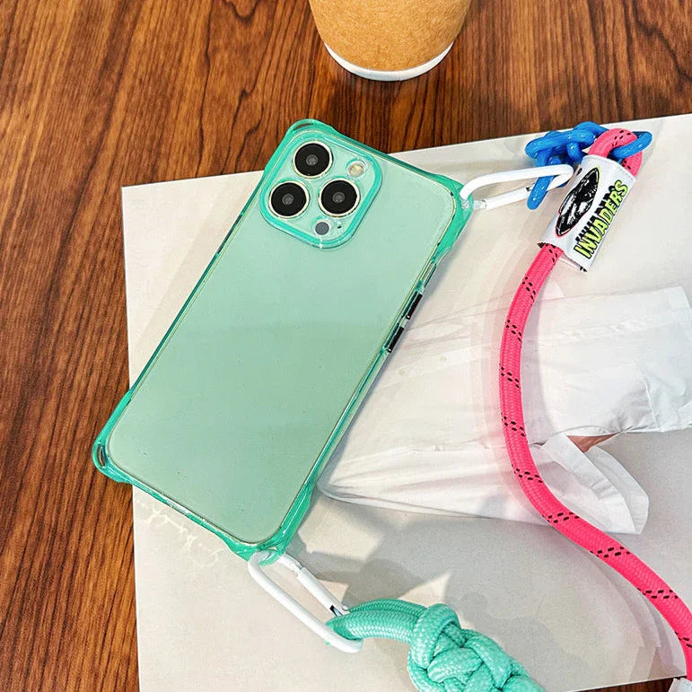 Coque fluo verte pour iPhone avec cordon multicolore INVADERS – vue lifestyle sur table en bois