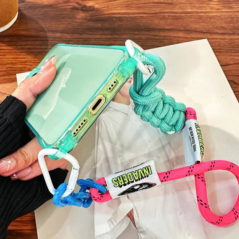 Vue rapprochée de la coque iPhone fluo verte tenue à la main, cordon rose et bleu enroulé
