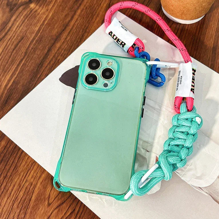 Coque iPhone verte fluo posée à plat avec cordon rose, bleu et tressage turquoise – style pop et pratique