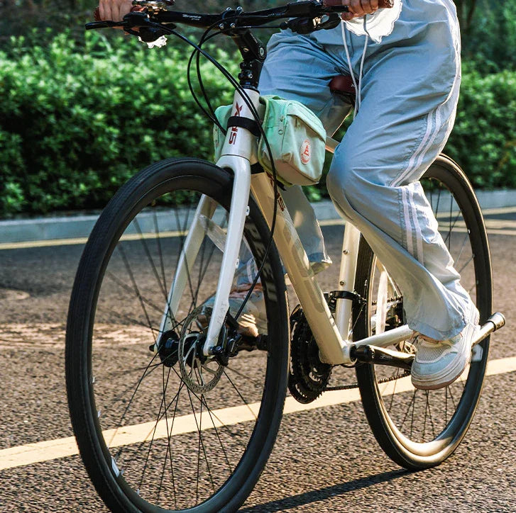 Cycliste féminine sur un vélo beige avec sac vert pastel – accessoire élégant en mouvement