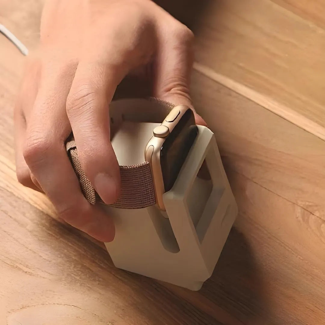 Utilisateur insérant une Apple Watch dans un support de recharge rétro couleur beige, sur une table en bois.