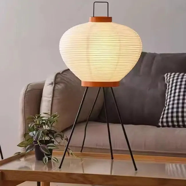 lampe en papier tripod posée sur table basse en bois devant un canapé