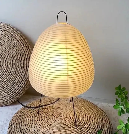 lampe papier paper moon allumée sur tapis tressé en paille