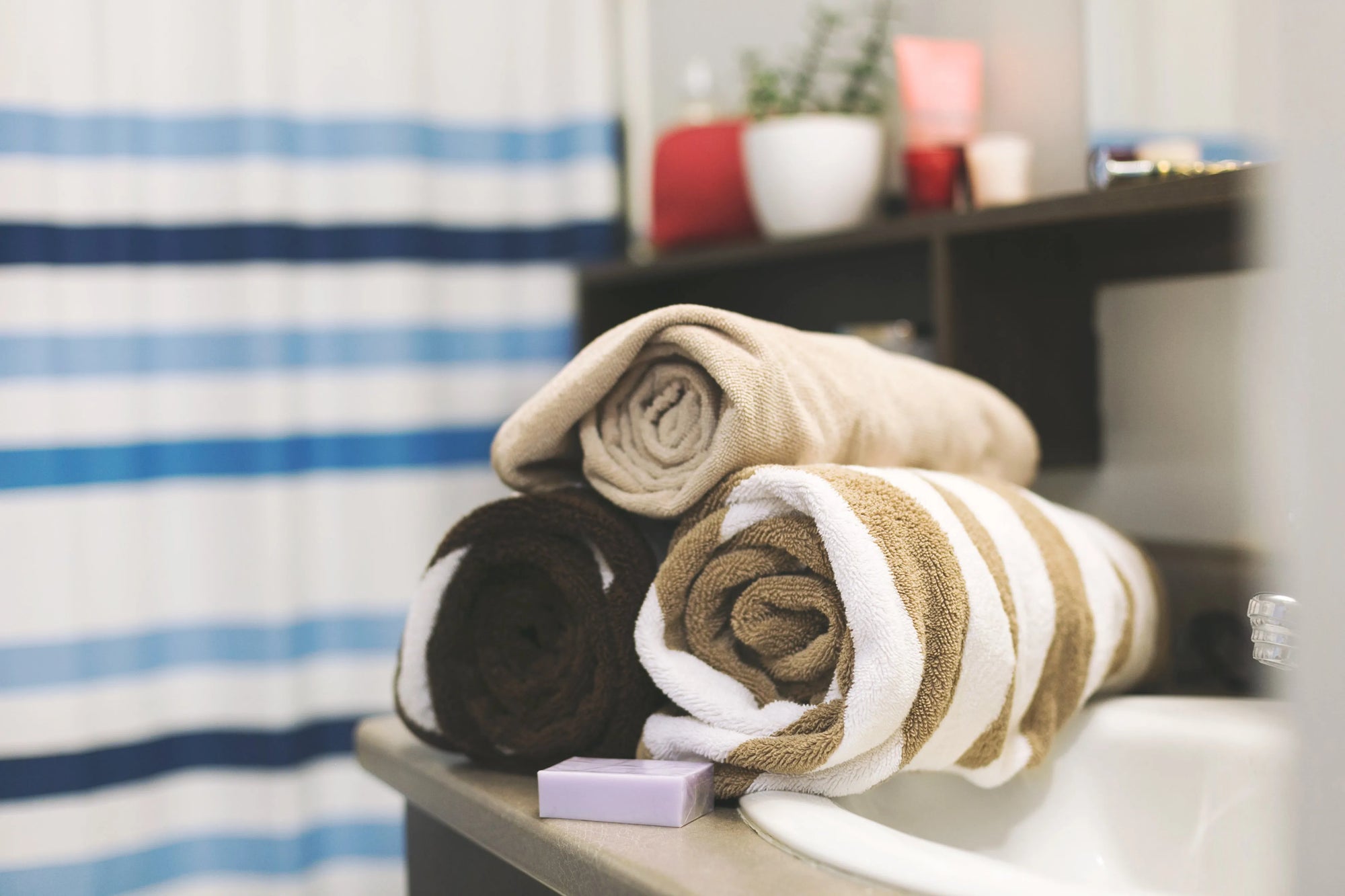 Serviettes de bain enroulées sur une étagère de salle de bain, ambiance spa et rangement soigné