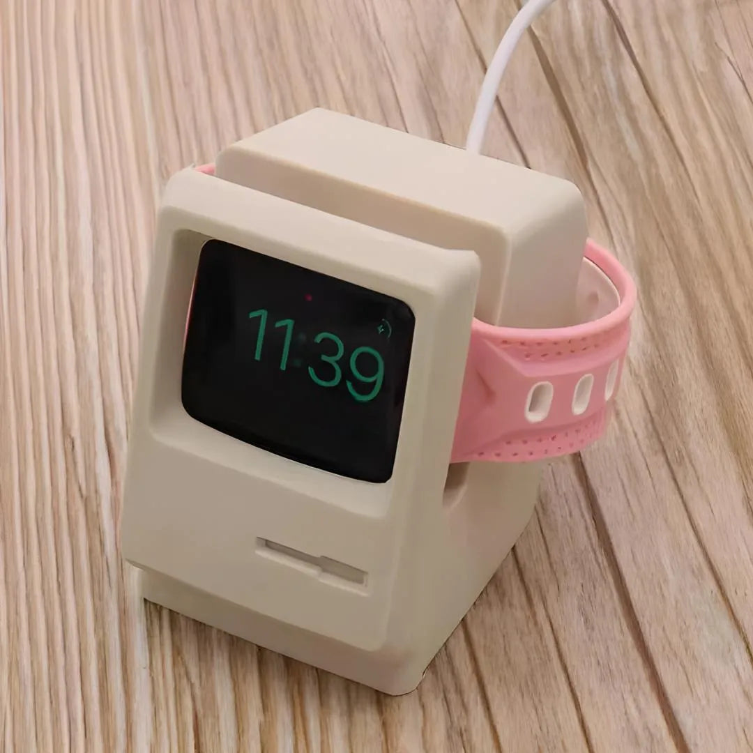 Support Apple Watch rétro beige avec câble de charge et bracelet rose, usage quotidien sur bureau.